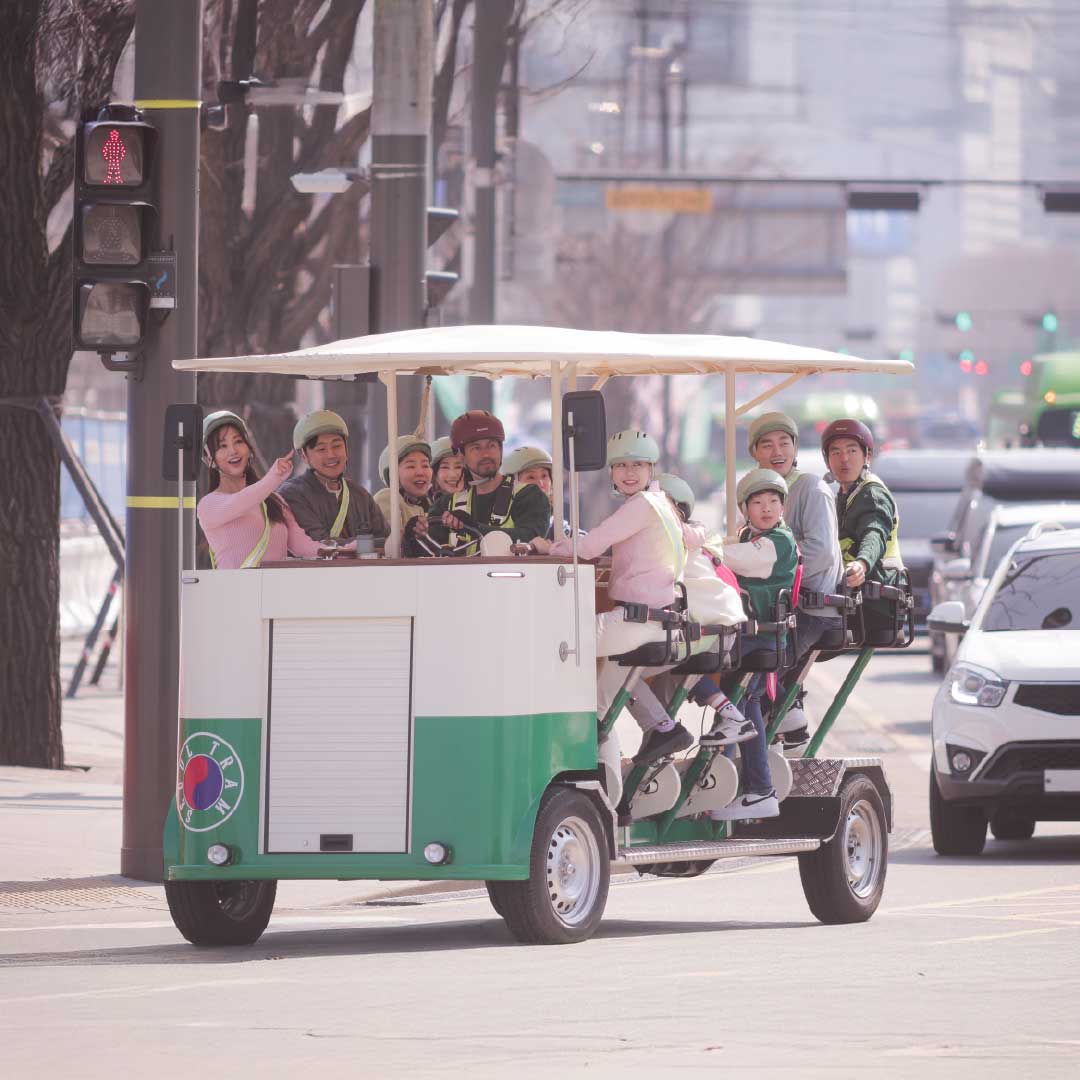 “A family enjoying a pedal-powered Seoul Tram ride through downtown on a sunny day.” “一家人在阳光明媚的日子里乘坐脚踏首尔电车穿梭市区。”