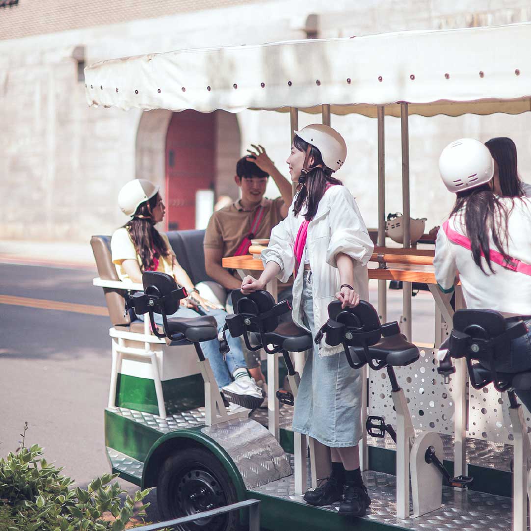 “Young women chatting and relaxing on a Seoul Tram with cafe-style seating.” “年轻女性在首尔电车上边骑边聊，享受咖啡厅般的座位氛围。”