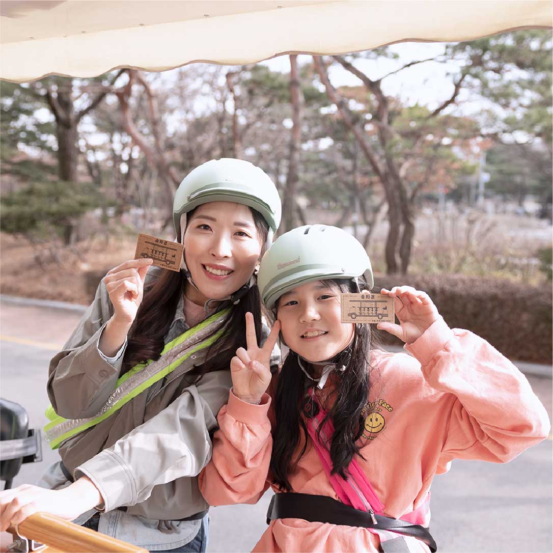 Mother and daughter holding Seoul Tram tickets and smiling 母女手持首尔电车票，开心合影留念