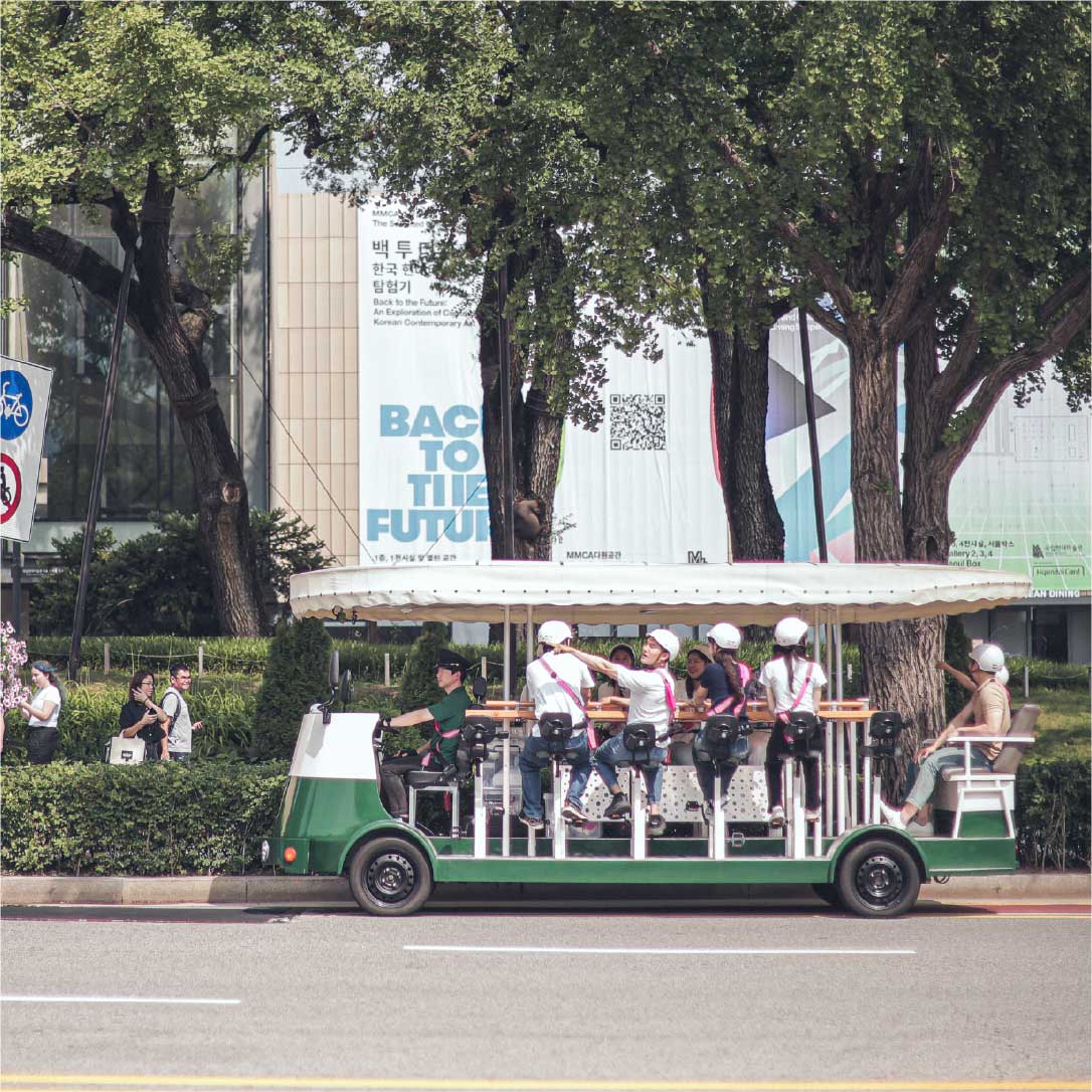Group riding the Seoul Tram near MMCA on a sunny summer day 夏日晴天，一群游客在国立现代美术馆前乘坐首尔电车