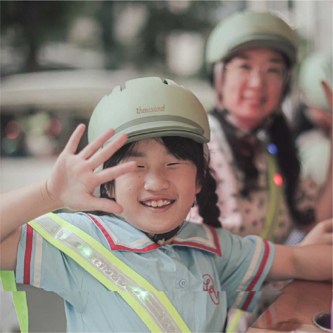 Child wearing helmet waving and smiling on the Seoul Tram 一名戴着头盔的小朋友在首尔电车上微笑挥手
