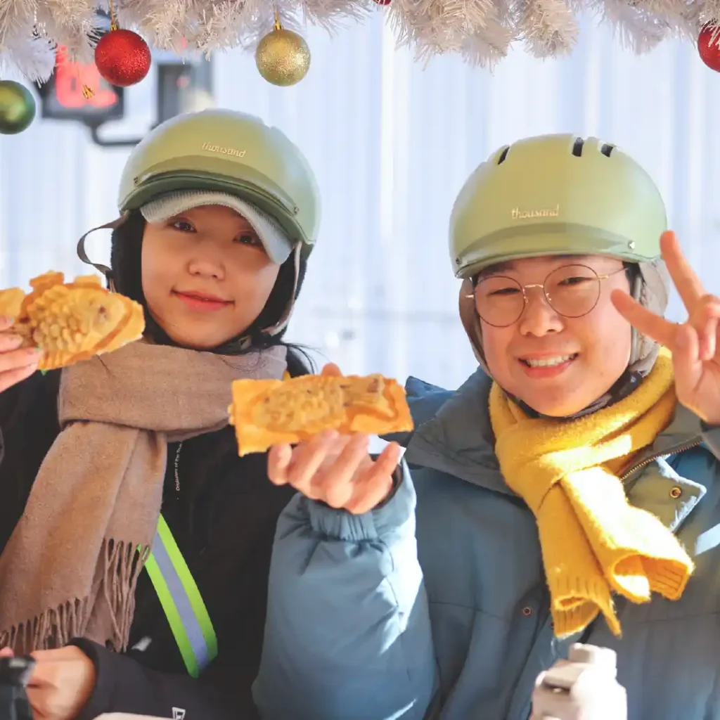 两位游客在冬季首尔电车上享用热腾腾的鲷鱼烧