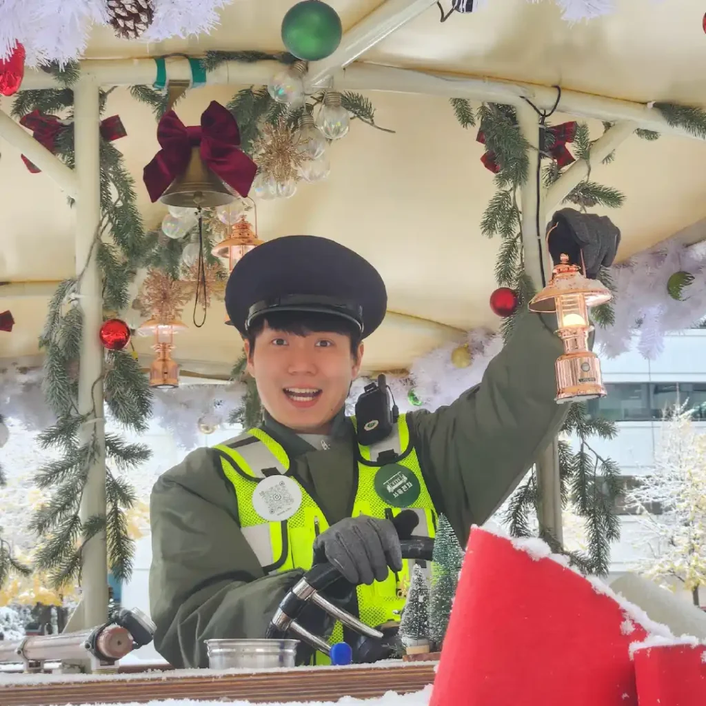一位穿制服的导游在圣诞装饰的电车上摇铃微笑。 Smiling guide in a uniform ringing a lantern bell on a Christmas-decorated tram.